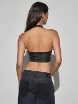 Top halter de cuero sintético negro con escote en V profundo, detalles de ojales metálicos y cordón ajustable frontal.