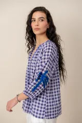 Camisa de manga larga con estampado a cuadros vichy en tonos azul y lila, escote en V y detalles bordados en el cuello, la botonera y las mangas.