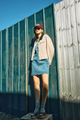 Chaqueta estilo worker de gabardina en color beige, con cuello camisero de cuerina negra, cierre frontal de cremallera y bolsillos frontales con cierre y ribete.