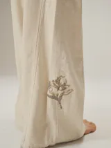 Pantalon de corte ancho y holgado, confeccionado en mezcla de algodón y lyocell. Presenta un diseño fluido con costuras verticales decorativas y bordado sutil en la pierna.
