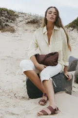 Sandalias planas de cuero negro con tiras anchas en el empeine y cierre ajustable con hebilla metálica en el talón.