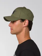Gorra de béisbol de color verde oliva con visera curvada y logotipo de Caterpillar bordado en negro en la parte frontal. Cuenta con tira trasera ajustable con cierre metálico.