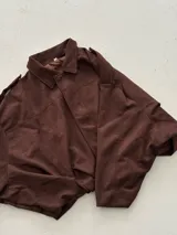 Chaqueta tipo bomber de efecto gamuza en color marrón, con cuello clásico, mangas anchas y ruedo elástico que genera un efecto fruncido.