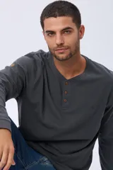 Remera de manga larga color gris oscuro, con cuello henley de tres botones y tejido texturado. Incluye un pequeño logo bordado en el pecho y un parche decorativo en la manga.