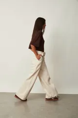 Jean azul oscuro de corte wide leg y tiro alto, con costuras pespunteadas verticales al frente y cinturón incorporado con hebilla cuadrada.