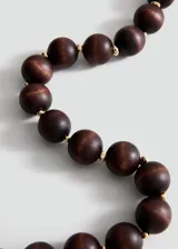 Collar de cuentas esféricas de madera en tonos marrones oscuros, separadas por pequeños abalorios metálicos dorados.