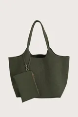 Bolso tipo tote de tejido de punto acanalado en color verde oliva, con diseño amplio y asas integradas. Incluye un pequeño neceser o monedero a juego sujeto por una correa con mosquetón.