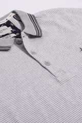 Remera de mangas cortas con cuello polo a rayas horizontales azul marino y blancas.