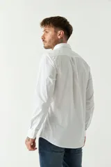 Camisa celeste de manga larga con logo bordado y bolsillo en el pecho.