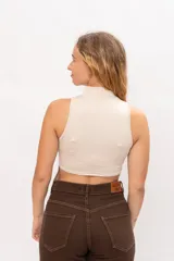 Top sin mangas con cuello alto tipo polera, confeccionado en tela elástica, con diseño de espalda corta.