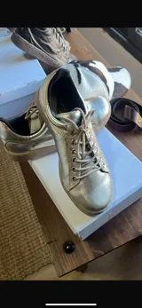 Zapatillas urbanas de cuero negro con suela blanca cosida y detalle de textura en el talón.