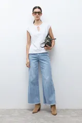 Remera blanca sin mangas con cuello redondo y abertura frontal tipo gota. Presenta un sutil diseño bordado en el frente y corte recto.