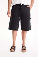 Bermuda de jean de algodón de estilo skater oversize en color negro, con diseño clásico de bolsillos y trabillas para cinto.