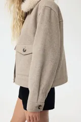 Campera de sarga con acabado cepillado, corte holgado y hombros caídos. Presenta un cuello extraíble de pelo sintético, cierre frontal con botones, bolsillos delanteros con solapa y puños abotonados.