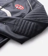 Campera biker de cuero sintético negro con detalles en blanco, cuello mao con broche, cierre frontal y parches bordados en el pecho. Presenta diseño acolchado en los hombros y mangas largas.
