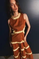 Vestido largo color marrón con volados amarillos en cuello, cintura y ruedo. Presenta recortes laterales en la cintura.