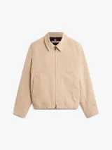 Campera Tommy Hilfiger modelo Ivy, color beige, confeccionada en tejido técnico impermeable y resistente al viento. Cuenta con cuello clásico, cierre frontal de cremallera, bolsillos laterales ribeteados y parche engomado en la manga.