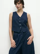 Chaleco azul marino con rayas verticales blancas, escote en V y cierre frontal con botones.