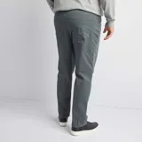 Pantalón de corte slim en color verde oscuro, con diseño de cinco bolsillos y cierre frontal con botón y cremallera.