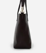 Cartera tipo shopper grande de Satinato, confeccionada en poliuretano con textura efecto crocco en color bordó. Cuenta con doble asa fija, correa larga desmontable con herrajes dorados y cierre superior por cremallera.