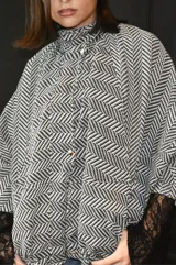 Campera tipo bomber oversize de paño italiano con estampado de espiga en blanco y negro. Presenta cuello alto, cierre frontal con botones metálicos y mangas estilo murciélago.