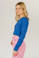 Top corto azul de tejido de punto acanalado, con mangas largas y cierre frontal con hebilla.