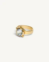 Anillo de banda ancha de plata con baño de oro, protagonizado por una piedra topacio facetada central enmarcada por pequeñas esferas.