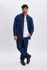 Sobrecamisa de jean color azul oscuro, de corte oversize, con mangas largas, bolsillos frontales con solapa y cierre con broches a presión.