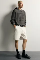 Sweater relaxed fit de algodón color gris con efecto lavado, cuello redondo, manga larga y diseño de textos estampados a contraste en el frente.