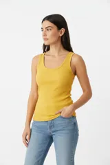 Musculosa al cuerpo de canalé, color amarillo mostaza, con escote redondo pronunciado y tirantes anchos.