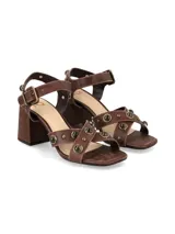 Sandalias de taco cuadrado alto y color marrón chocolate, con tiras anchas en el empeine decoradas con tachas metálicas y tira ajustable con hebilla en el tobillo.