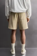 Short jogger marrón de corte relaxed fit, confeccionado en tejido compacto de algodón, con cintura elástica ajustable, bolsillos frontales en la cadera y bolsillo trasero de plastrón.