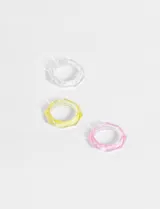 Set de tres anillos transparentes de acrílico, uno transparente, uno amarillo y uno rosa. De forma irregular y tamaño 18mm.