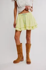 Minifalda amarilla de algodón con cintura elástica ajustable mediante cordón, diseño de doble volante con bordes festoneados y detalles de puntilla.