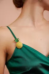 Broche prendedor con forma de ananá con cuerpo de strass amarillos y hojas verdes.
