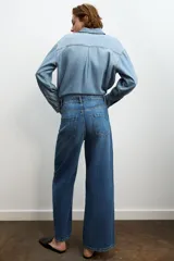 Jeans de tiro alto con diseño de pierna ancha y cinco bolsillos. Cuenta con cierre frontal mediante cremallera y botón metálico.