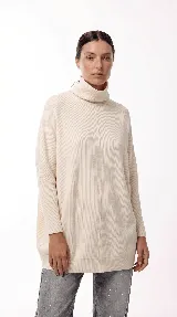 Sweater oversize de punto con cuello polera amplio, diseño holgado y mangas largas con puños ajustados. Presenta una costura vertical central en el frente.