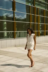 Chaleco de punto color blanco roto, sin mangas, con cuello polo y abertura en V con cordones terminados en borlas.