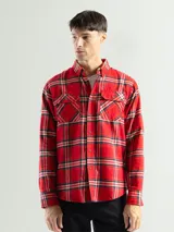 Camisa de franela a cuadros color celeste, gris y negro, de manga larga con dos bolsillos frontales con solapa abotonada.