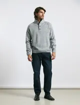 Sweater de punto color azul marino, con cuello alto, cierre frontal parcial y tapeta con botones. Presenta mangas raglán y puños y ruedo acanalados.