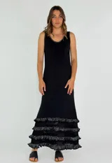 Vestido largo negro con breteles finos y escote redondo. Presenta tres volados de encaje calado en el ruedo.