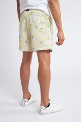 Short de baño con cintura elástica y cordón ajustable, confeccionado en tela ligera de secado rápido. Presenta un estampado botánico integral en tonos amarillos, blancos y azules, con dos bolsillos delanteros y uno posterior.
