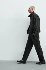 Jeans de denim de algodón en color negro con efecto lavado, corte amplio y silueta curva tipo barrel fit con pinzas en las rodillas. Presenta diseño clásico de cinco bolsillos y cierre frontal con cremallera y botón metálico.