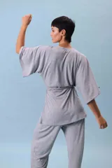 Conjunto de dos piezas (camisa y pantalón) de tejido acanalado gris, con camisa estilo kimono de manga ancha y cuello V cruzado, ajustada a la cintura con un lazo de tela.