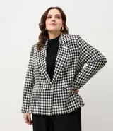 Blazer de sastrería confeccionado en tejido tweed con estampado pied de poule en blanco y negro. Presenta cuello con solapa, cierre frontal con un botón, mangas largas y bolsillos frontales con solapa.