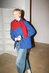 Chaqueta azul de corte recto, con cuello camisero, manga larga y cierre frontal de botones metálicos. Cuenta con un bolsillo de parche en el pecho y dos bolsillos con solapa en la parte inferior delantera.