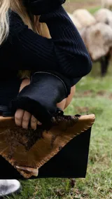 Sobre de cuero color rojo y negro con diseño de vaca y cierre con botón de guampa.