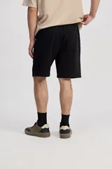 Bermuda de caída suelta con cintura elastizada y cordón regulable, confeccionada en tejido texturado negro.
