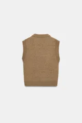 Chaleco de punto en color verde oliva, con escote en pico y sisas amplias. Presenta terminaciones acanaladas en el cuello, las sisas y el ruedo.