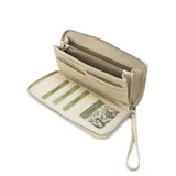 Billetera larga con cierre perimetral, confeccionada en material sintético texturizado color mostaza. Cuenta con correa de mano extraíble y placa metálica con logo de la marca en el frente.